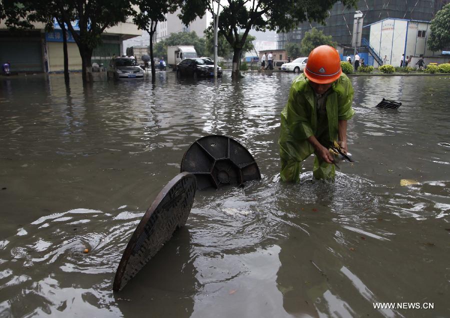 A sanitation worker opens manhole covers on a flooded road in Jinjiang City, southeast China's Fujian Province, May 16, 2013. A torrential rainfall hit the city overnight, flooding many roads in the city. (Xinhua)