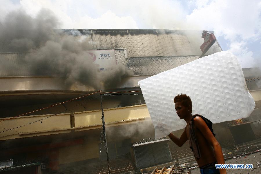 A man evacuates from the fire accident site in Manila, the Philippines, May 16, 2013. Two people were rescued from the fire, as firefighters estimate the fire may last for two days. (Xinhua/Rouelle Umali) 