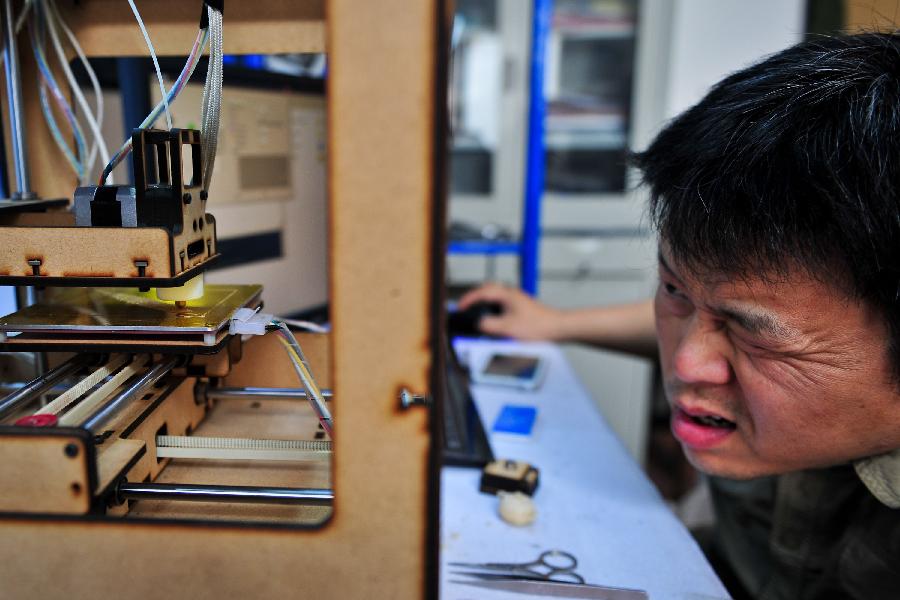 Han Bing checks his handmade 3D printer in Tianjin Municipality, north China, May 16, 2013. Based on the method released on the internet, the 41-year-old by himself made this machine eventually, which costing some 2,000 RMB yuan (325 U.S. dollars) and spending four months. At present, Han's 3D printer could only make simple items designed on the computer, like teapots and whistles. And he hopes his creation could function more powerfully by continuous improvement. (Xinhua/Zhang Chaoqun) 