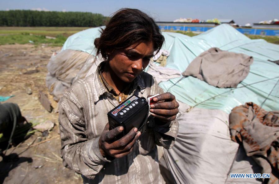 A Hindu girl adjusts a pen drive to her recorder at a slum area near Bijbehara town of Anantnag district, around 44 km south of Srinagar city, the summer capital of Indian-controlled Kashmir, May 16, 2013. Thousands of poor Hindu labourers from Indian states migrate to Indian-controlled Kashmir during summers to escape the scorching heat and earn their livelihood by either doing menial jobs or selling brooms. (Xinhua/Javed Dar)