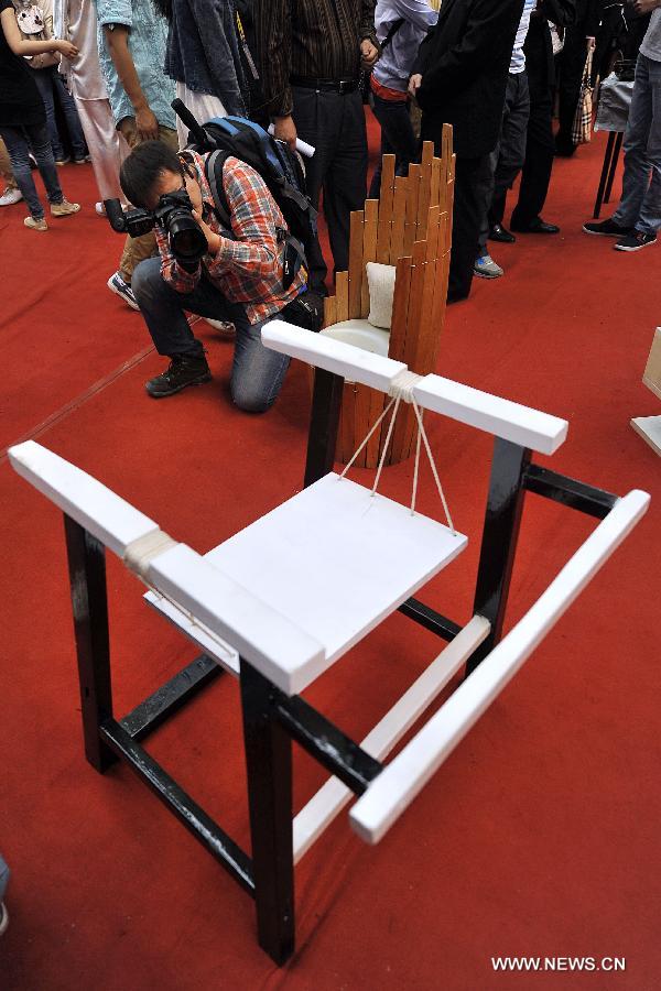 A man takes pictures of a chair made of recycled wood at the 2013 creativity fair in Taiyuan University of Technology in Taiyuan, capital of north China's Shanxi Province, May 17, 2013. (Xinhua/Zhan Yan)   
