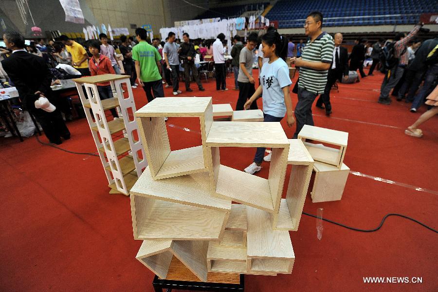People walk past furniture made of recycled wood at the 2013 creativity fair in Taiyuan University of Technology in Taiyuan, capital of north China's Shanxi Province, May 17, 2013. (Xinhua/Zhan Yan)