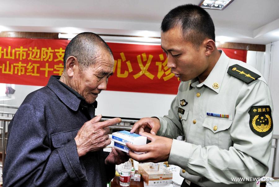 A policeman introduces medicine information to a patient in Daishan County, Zhoushan City, east China's Zhejiang Province, May 17, 2013. A medical service team, formed by medical workers from the Zhoushan detachment of the provincial Frontier Defence Department and some doctors from the local Red Cross Society, provided free medical treatments to residents here on Friday. (Xinhua/Xu Yu) 