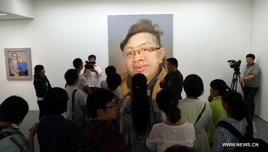 Visitors gather to watch oil paintings at an exhibition of Chinese realistic painter Xin Dongwang's works in Beijing, capital of China, May 17, 2013. (Xinhua/Zhang Yanhui)  