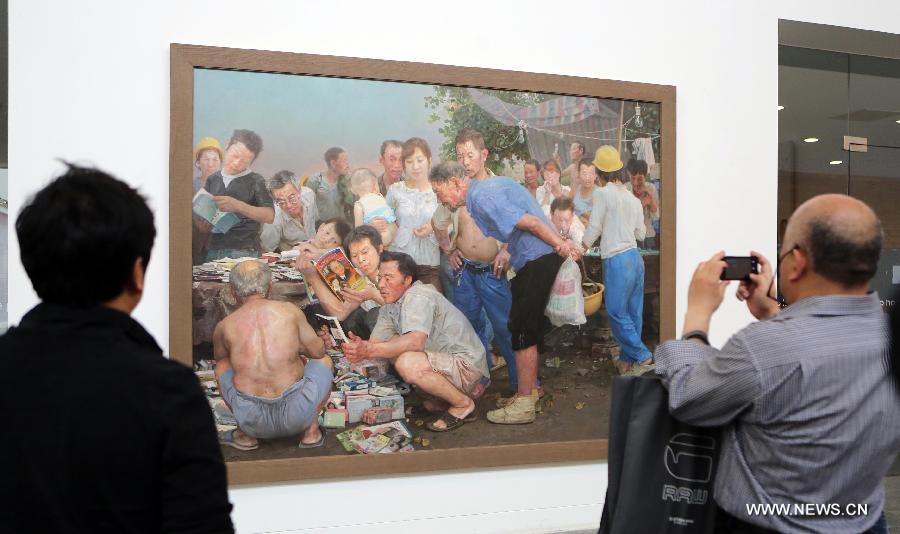 Visitors watch oil paintings at an exhibition of Chinese realistic painter Xin Dongwang's works in Beijing, capital of China, May 17, 2013. (Xinhua/Zhang Yanhui)  