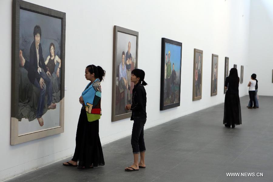 Visitors watch oil paintings at an exhibition of Chinese realistic painter Xin Dongwang's works in Beijing, capital of China, May 17, 2013. (Xinhua/Zhang Yanhui)  