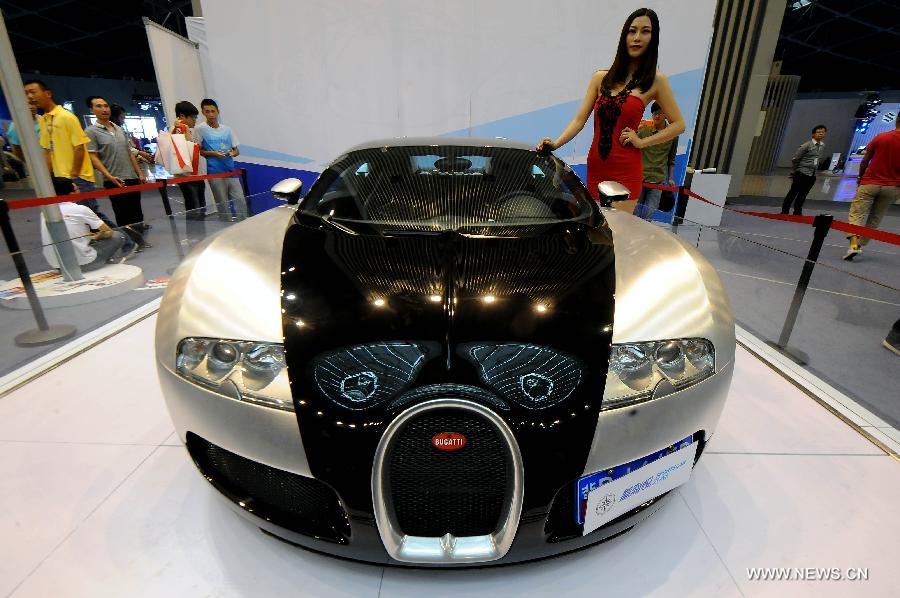 A model presents a Bugatti Veyron at the 2013 China (Taiyuan) International Automobile Exhibition in Taiyuan, capital of north China's Shanxi Province, May 17, 2013. Some 400 vehicles of 63 brands were taken to the auto show here, which kicked off on May 16. (Xinhua/Fan Minda) 