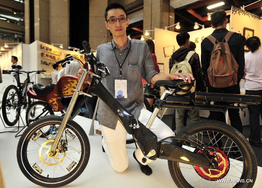 A staff member shows a folding electric bike at the 2013 Youth Designers' Exhibition (YODEX) in Taipei, southeast China's Taiwan, May 17, 2013. It could run 30 km on a single charge. The 2013 YODEX, opening Friday in Taipei, attracted over 8,400 designers. (Xinhua/Wu Ching-teng)