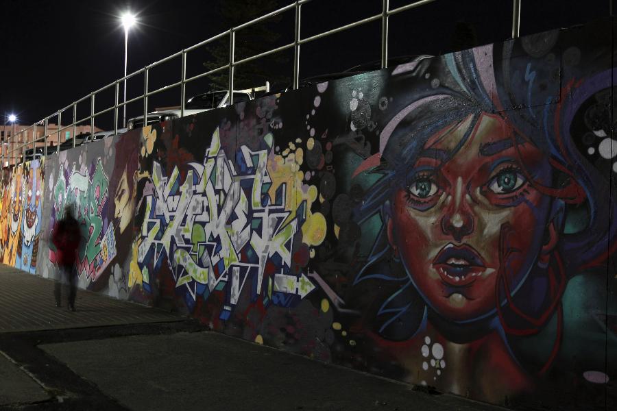 A visitor walks past the Chloe Memorial Mural on the Bondi Beach in Sydney, Australia, May 17, 2013. The 15-year-old Chloe Byron was one of the 202 victims of the Bali bombing on Oct. 12, 2002. With the support of Chloe's family, local aerosol artists completed the Chloe Memorial Mural on the beach where she grew up in memory of Chloe and other victims. The local council have commissioned the artists to recreate the murals which are in need of repair. (Xinhua/Jin Linpeng) 