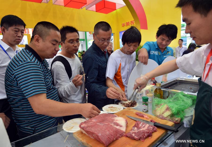 Visitors taste toasted beef at the 11th (2013) China Animal Husbandry Expo in Wuhan, capital of central China's Hubei Province, May 18, 2013. The expo, which kicks off on May 18, will last until May 21. (Xinhua/Hu Weiming)