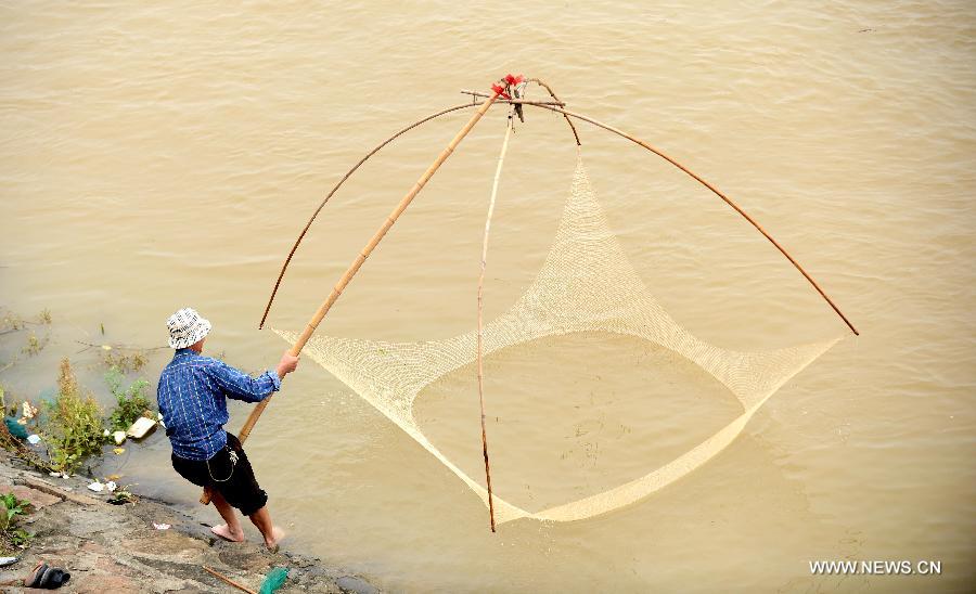 A citizen fishes from the Ganjiang River in Nanchang, capital of east China's Jiangxi Province, May 19, 2013. The rainfall from May 14 has pushed up the water level of the Ganjiang River, which has reached 18.95 meters by 8 a.m. on April 19, the highest level of this year. (Xinhua/Zhou Ke) 