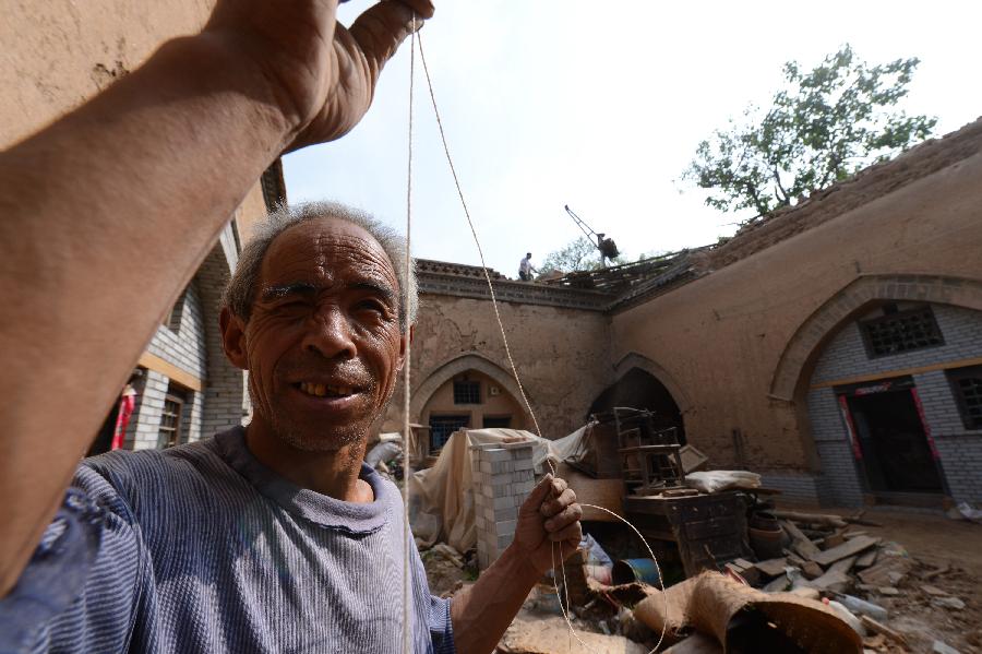 A construction worker renovates a sunken courtyard in Qucun Village of Zhangbian Township in Shanxian County, central China's Henan Province, May 18, 2013. The sunken courtyard, a kind of traditional residential construction in west Henan, has a high value in the study of local histroy, architecture, geology and sociology. The Qucun Village has 115 sunken courtyards, most of which are under protective reconstruction. (Xinhua/Zhao Peng) 