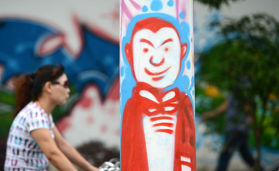 Photo taken on May 19, 2013 shows a telegraph pole decorated with graffiti in Nanchang, capital of east China's Jiangxi Province. Two graduates from the Academy of Arts and Design in Hunan University of Science and Technology designed those graffiti to express their opinions of fashion. (Xinhua/Zhou Ke)