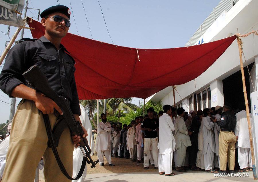 HA Pakistani policeman stands guard as people stand in a queue outside a polling station during the partial re-run election in southern Pakistani port city of Karachi, May 19, 2013. Re-polling on a parliamentary seat started in Pakistan's port city of Karachi Sunday morning following allegations of rigging, officials said. (Xinhua/Arshad) 