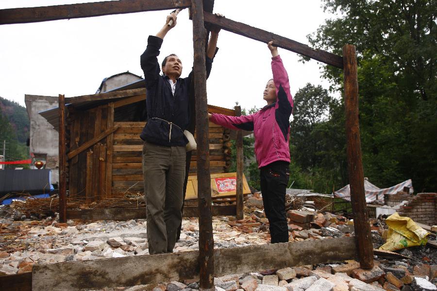 48-year-old Cheng Guowu (L) and his wife try to build a house on ruins in Gucheng Village in Longmen Town, southwest China's Sichuan Province, May 17, 2013. Villagers who were affected by the earthquake that jolted the region on April 20 are rebuilding their houses with building materials recovered from the ruins. (Xinhua/Cui Xinyu)