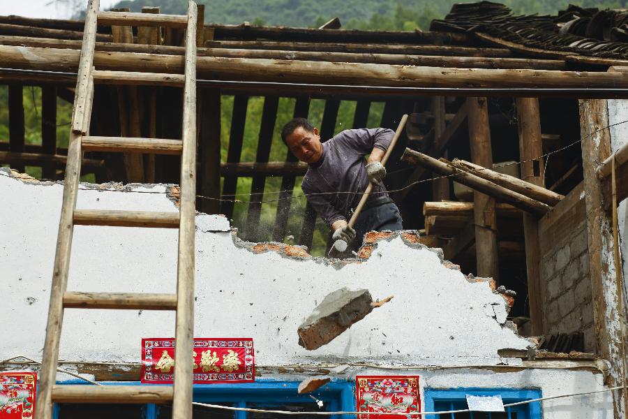 A villager pulls down dangerous houses in Xiangshuixi Village in Tianquan County, southwest China's Sichuan Province, May 18, 2013. Villagers who were affected by the earthquake that jolted the region on April 20 are rebuilding their houses with building materials recovered from the ruins. (Xinhua/Cui Xinyu)
