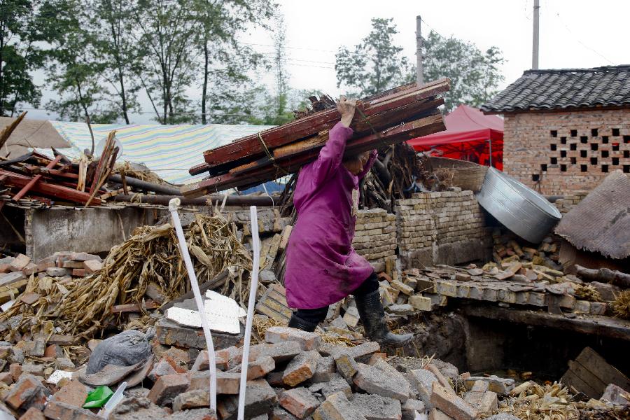 A woman carries timber for reconstruction in Gucheng Village in Longmen Town, southwest China's Sichuan Province, May 17, 2013. Villagers who were affected by the earthquake that jolted the region on April 20 are rebuilding their houses with building materials recovered from the ruins. (Xinhua/Cui Xinyu)