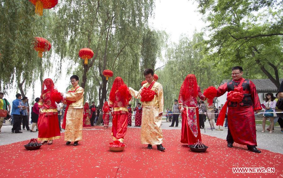 Newlyweds step over "braziers", a symbol of good luck, during a group wedding held in the Old Summer Palace, or Yuanmingyuan park, in Beijing, China, May 18, 2013. A total of 30 couples of newlyweds took part in event with traditional Chinese style here on Saturday. (Xinhua/Zhao Bing) 