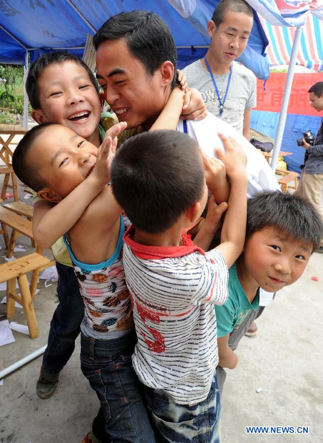 A psychological aid volunteer plays games with children at a psychological support workstation set up by the Chinese Academy of Sciences (CAS) in the Xinfeng Community in the quake-hit Lushan County, southwest China's Sichuan Province, May 14, 2013.  (Xinhua/Li Xiaoguo)