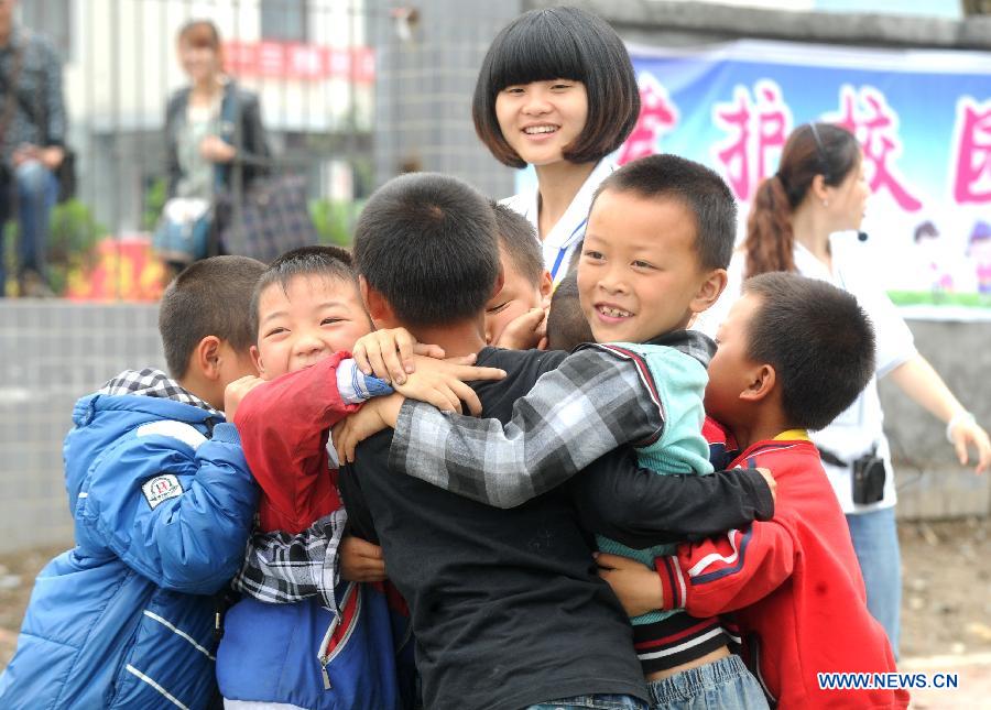 A psychological aid volunteer plays game with children at a psychological support workstation set up by the Chinese Academy of Sciences (CAS) inside a makeshift school in the quake-hit Lushan County, southwest China's Sichuan Province, May 15, 2013. The CAS has set up four psychological support workstations scattered in the disaster areas in the wake of the Lushan disaster so as to provide psychological intervention to help local survivors deal with the quake's emotional impact and move on. By far, a total of ten specialists and 32 volunteers were sent by the CAS's Institute of Psychology and helped more than 1,000 people. (Xinhua/Li Xiaoguo) 