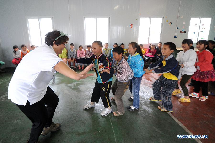 A psychological aid volunteer plays game with children at a psychological support workstation set up by the Chinese Academy of Sciences (CAS) in a makeshift school in the quake-hit Lushan County, southwest China's Sichuan Province, May 14, 2013.(Xinhua/Li Xiaoguo) 