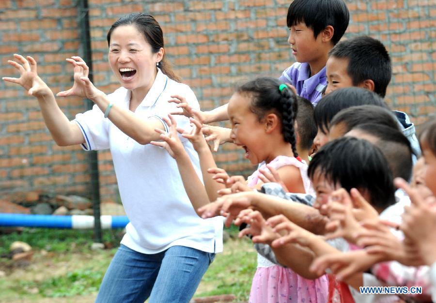 A volunteer plays games with children before a psychological support course at a psychological support workstation joined by the Chinese Academy of Sciences (CAS) inside a school in the quake-hit Lushan County, southwest China's Sichuan Province, May 14, 2013. (Xinhua/Li Xiaoguo) 