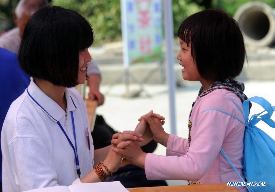 A psychological aid volunteer plays game with a girl at a psychological support workstation set up by the Chinese Academy of Sciences (CAS) in the Xinfeng Community in the quake-hit Lushan County, southwest China's Sichuan Province, May 13, 2013.  (Xinhua/Li Xiaoguo)