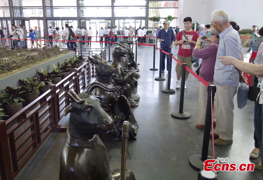 Visitors take photos for the 1:150 scale replicas of the 12 bronze sculptures of animal heads that formerly guarded a building in Yuanmingyuan Park, the old Imperial Summer Palace, at the Garden Expo Park in Fengtai District, Beijing, May 19, 2013. The Ninth China (Beijing International Garden Expo kicked off on Saturday. Garden designs from 69 Chinese cities and 29 countries will be presented. (CNS/Liu Guanguan)