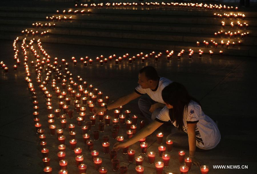 People light candles during a commemoration event for the people that died on consequence of Human Immunodeficiency Virus (HIV), organized by the Atlacatl Association Vivo Positivo, at the Salvador del Mundo Square, in San Salvador, capital of El Salvador, on May 19, 2013. A total of 4,000 candles were lit during the event. (Xinhua/Oscar Rivera)