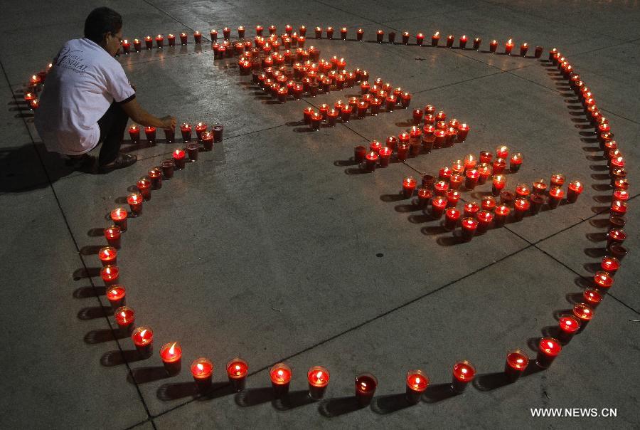 A woman lights candles during a commemoration event for the people that died on consequence of Human Immunodeficiency Virus (HIV), organized by the Atlacatl Association Vivo Positivo, at the Salvador del Mundo Square, in San Salvador, capital of El Salvador, on May 19, 2013. A total of 4,000 candles were lit during the event. (Xinhua/Oscar Rivera)