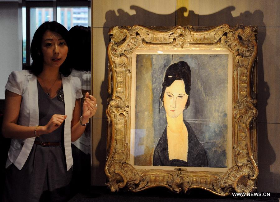 A worker introduces an oil painting during the preview of Est-Ouest Auctions' spring season auction in south China's Hong Kong, May 20, 2013. The preview of Est-Ouest Auctions' 2013 spring season auction opened here on Monday, and the auction will be held in Hong Kong on May 26. (Xinhua/Huang Benqiang)