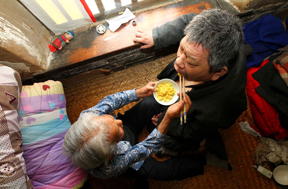 Cao Xiuying feeds her son at home in Weifang city of Shandong on May 11, 2013. Cao, 86, lives in a village in east China's Shandong province. Her son, Zhao Dequan, became mentally disabled because of viral encephalitis when he was eight months old. After Cao's husband died eight years ago, Cao had to take care of her son alone. Her son has never called her mother in 58 years. However, Cao uses her whole life to prove what a mother's love is. (Xinhua/Sun Shubao) 