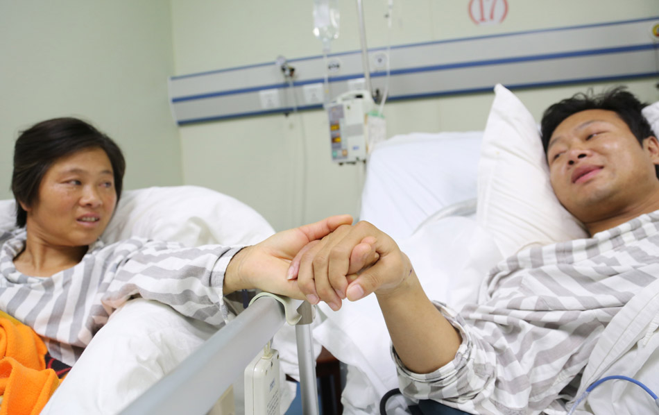 Yuan Bo holds the hand of his mother Tang Aifeng in the ICU ward of Nanhua hospital in Hengyang , Hunan province on May 12, 2013. It was the Mother's Day. The best gift for Tang was the recovery of her son. Yuan was diagnosed with advanced uremia at the end of 2012. His mother donated a kidney to save his life. (Xinhua/Cao Zhengping)