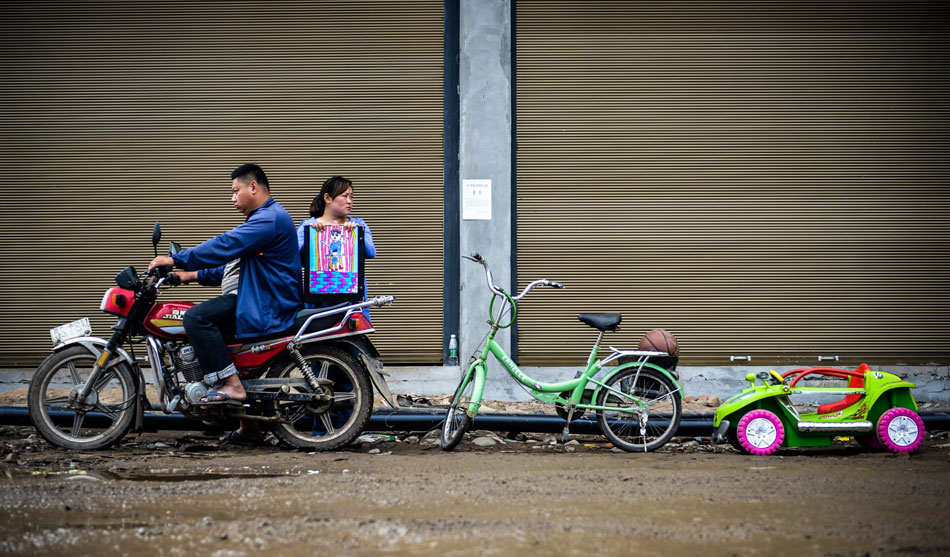 Zheng Yong rides on a motorcycle, and his wife Xiaoli holding a picture drawn by their son stands at his side and watches the bicycle, toy and basketball of their son. Sometimes, they felt their son were still with them. Their only son Zheng Chaoyi, 8, died in the Lushan Earthquake on April 20, 2013. (Xinhua/Bai Yu)