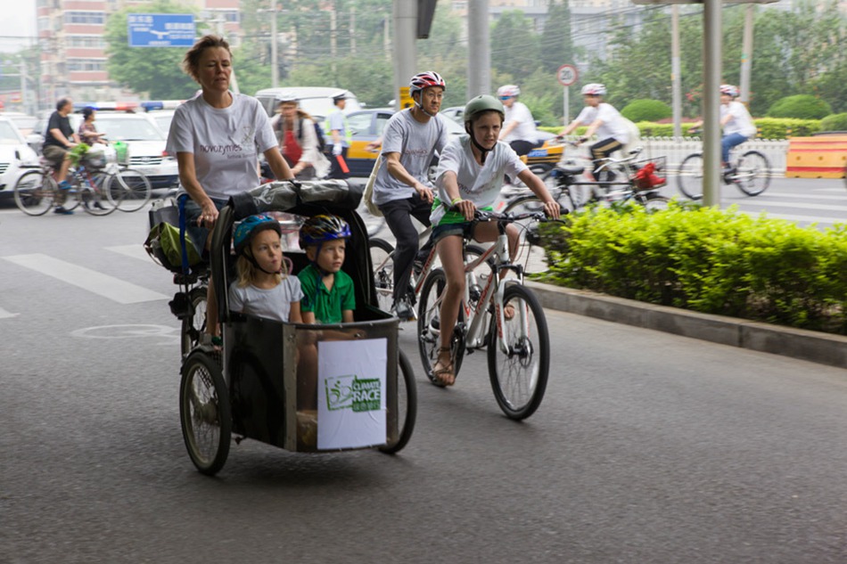 A mother participating in the cycling race rides a Christiana bike with her children in the Sanlitun area of Beijing. The Danish Embassy in China organized the "Climate Race" together with the China Cycling Association and Yanqing County inside and outside Beijing in order to raise awareness of modern urban green lifestyles on Sunday, May 19, 2013. [Photo: CRIENGLISH.com/ Cui Chaoqun]