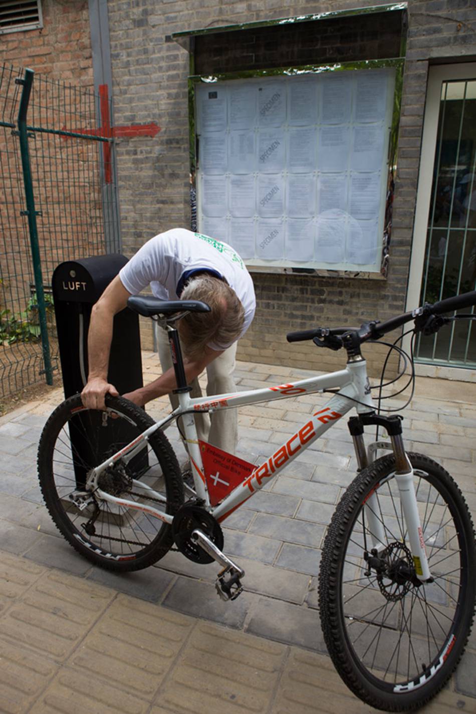 Arne Petersen, Denmark's ambassador to China, demonstrates how to use the 24-hour bicycle pump at the Danish Embassy in Beijing, so cyclists passing by can pump up their tires for free. [Photo: CRIENGLISH.com/ Cui Chaoqun]