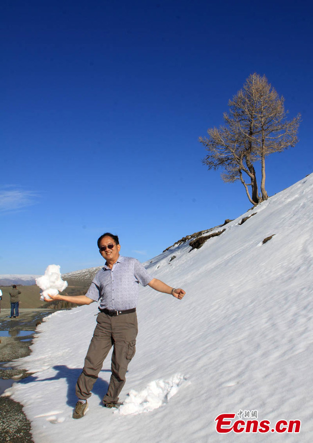 A man poses for photos at the foot of snow-capped mountain in Baishitou County, Hami, Northwest China's Xinjiang Uygur Autonomous Region. Tourists can enjoy sceneries of spring, summer, fall and winter at the same time in the county. (CNS/Cao Xinjiang)