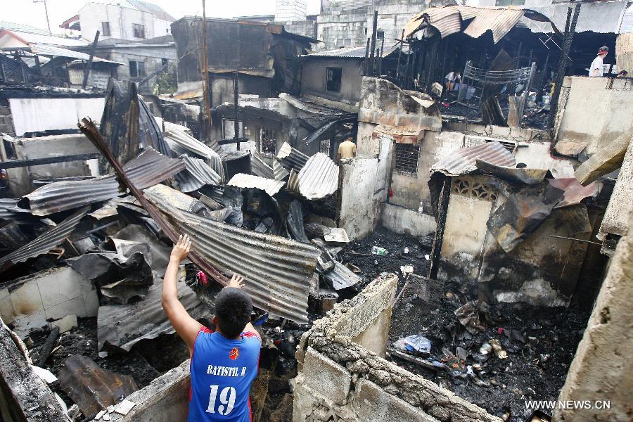 A resident retrieves reusable materials from his burnt homes after a fire razed a residential area in Quezon City, the Philippines, May 21, 2013. More than 200 families were left homeless in the fire. (Xinhua/Rouelle Umali)