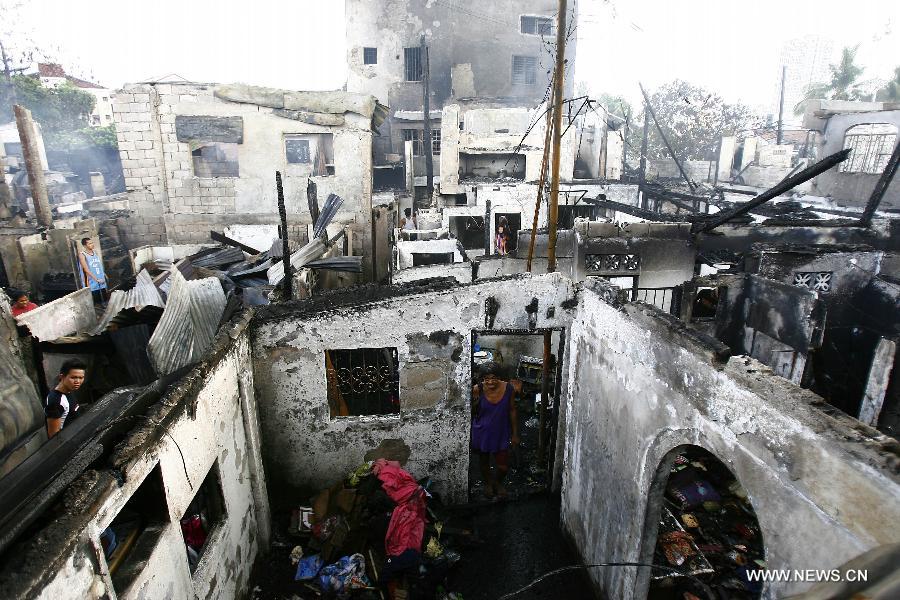 Residents retrieve reusable materials from their burnt homes after a fire razed a residential area in Quezon City, the Philippines, May 21, 2013. More than 200 families were left homeless in the fire. (Xinhua/Rouelle Umali)