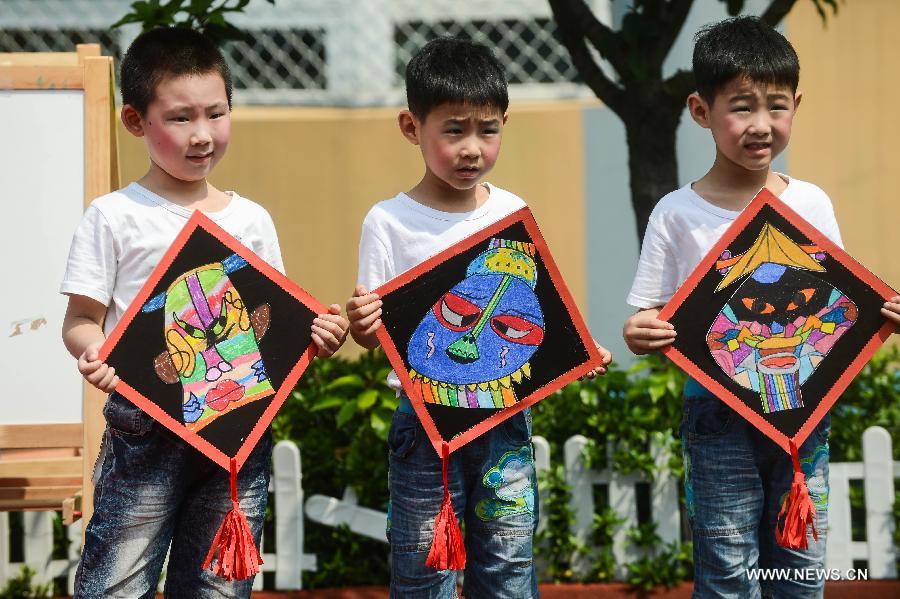 Children demonstrate mask-paintings in a kindergarten in Hangzhou, capital of east China's Zhejiang Province, May 21, 2013. An activity for children to present their ideas and creations was held to celebrate the coming Children's Day. (Xinhua/Xu Yu) 