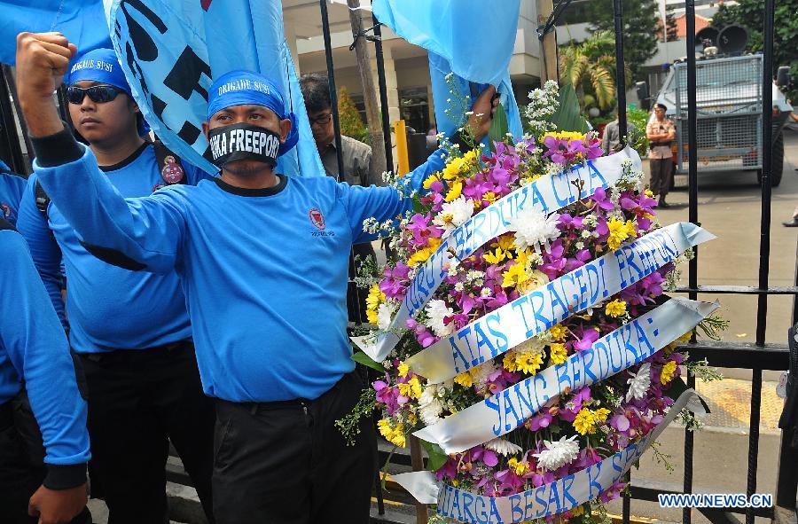 Indonesian workers carry flowers during a rally in front of the Ministry of Energy and Mineral Resources in Jakarta, Indonesia, May 21, 2013. The number of casualties in underground mine collapse at Big Gossan mine of Freeport McMorant Coppert and Gold Inc rose to 21 with 7 others remained being trapped, a statement from the firm said here Tuesday. (Xinhua/Zulkarnain)