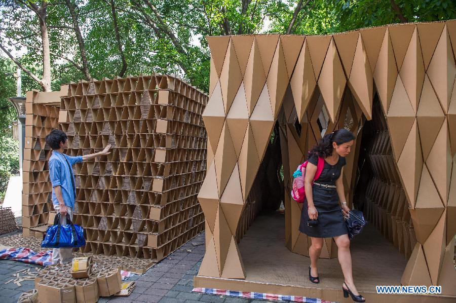 People visit paper houses in the Chongqing University, Chongqing, southwest China, May 21, 2013. Fourteen paper houses, made up with recycled paper by more than 200 freshman, were displayed in the Faculty of Architecture and Urban Planning of the university on Tuesday. (Xinhua/Chen Cheng)
