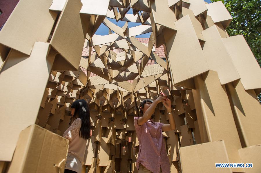 Students take photos in a paper house in the Chongqing University, Chongqing, southwest China, May 21, 2013. Fourteen paper houses, made up with recycled paper by more than 200 freshmen, were displayed in the Faculty of Architecture and Urban Planning of the university on Tuesday. (Xinhua/Chen Cheng)