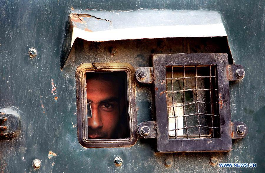An Indian policeman peeps through a police vehicle outside the separatist party's office in Srinagar, Indian-controled Kashmir, on May 21, 2013. A shutdown called by separatists to mark the anniversaries of two killed separatist leaders Mirwaiz Muhammed Farooq and Abdul Gani Lone was observed here on Tuesday. Authorities have placed moderate separatist leader Mirwaiz Umar Farooq under house arrest. (Xinhua/Javed Dar)
