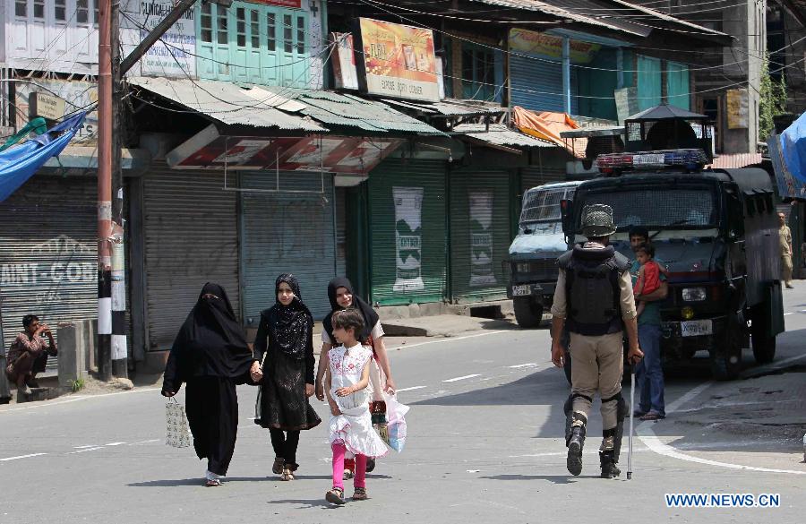 A Kashmiri Muslim family walk past an Indian policeman in a closed market during a strike in Srinagar, Indian-controled Kashmir, on May 21, 2013. A shutdown called by separatists to mark the anniversaries of two killed separatist leaders Mirwaiz Muhammed Farooq and Abdul Gani Lone was observed here on Tuesday. Authorities have placed moderate separatist leader Mirwaiz Umar Farooq under house arrest. (Xinhua/Javed Dar)