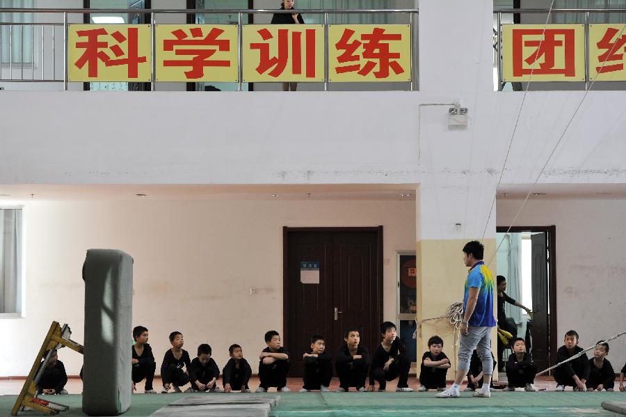 Yao Xing, deputy principal of an acrobatics troupe, instructs students at a training area in Yinchuan, capital of northwest China's Ningxia Hui Autonomous Region, May 20, 2013. Established in 1958, the acrobatics troupe was now affiliated with Ningxia Yinchuan Art Theatre. During the past few years, over 30 children between 5 and 13 years old have been admitted to the troupe to exercise acrobatics. In order to perform well on the stage, they exert much effort on exercising. Besides, they also learn general courses such as maths, Chinese and English. Yao Xing, deputy principal of the troupe, said that acrobatics requires painstaking effort, which will pay off one day. (Xinhua/Peng Zhaozhi)
