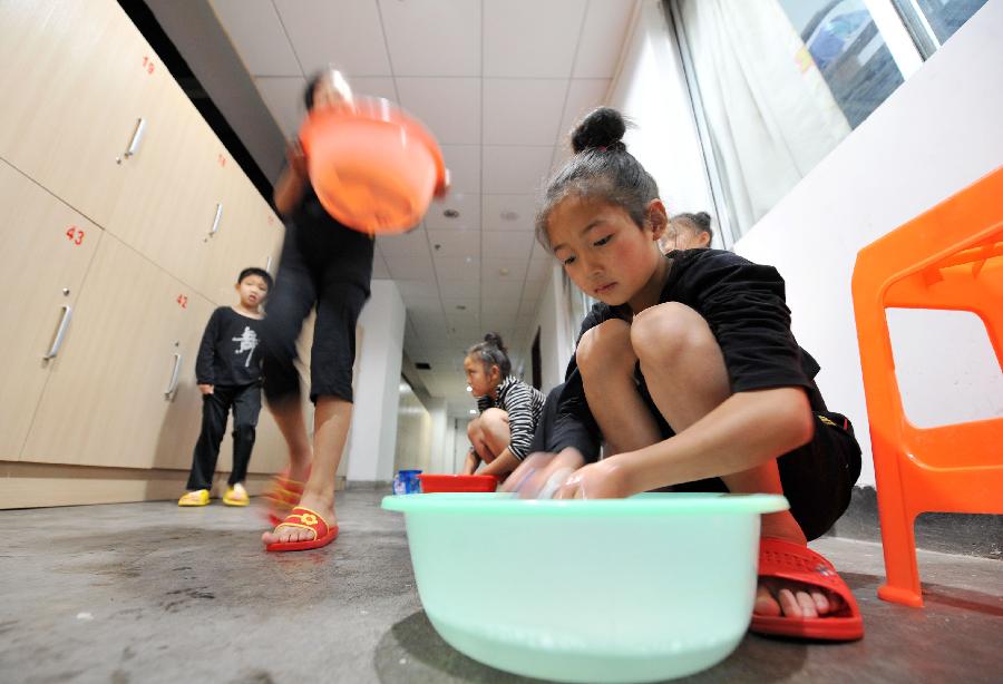 Ma Rongge, a student of an acrobatics troupe, washes her socks in her dorm in Yinchuan, capital of northwest China's Ningxia Hui Autonomous Region, May 20, 2013. Established in 1958, the acrobatics troupe was now affiliated with Ningxia Yinchuan Art Theatre. During the past few years, over 30 children between 5 and 13 years old have been admitted to the troupe to exercise acrobatics. In order to perform well on the stage, they exert much effort on exercising. Besides, they also learn general courses such as maths, Chinese and English. Yao Xing, deputy principal of the troupe, said that acrobatics requires painstaking effort, which will pay off one day. (Xinhua/Peng Zhaozhi)