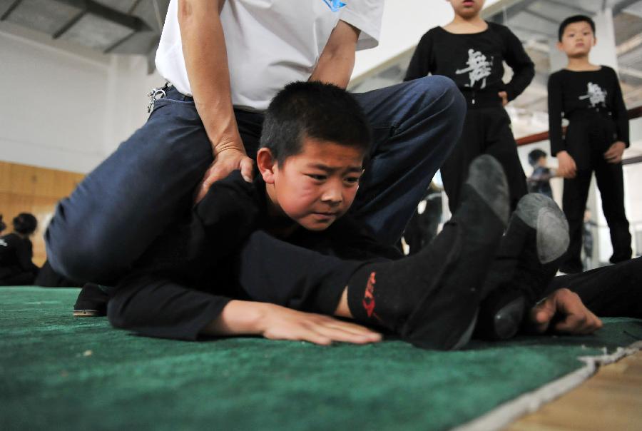 Children of an acrobatic troupe exercise at a training area in Yinchuan, capital of northwest China's Ningxia Hui Autonomous Region, May 21, 2013. Established in 1958, the acrobatics troupe was now affiliated with Ningxia Yinchuan Art Theatre. During the past few years, over 30 children between 5 and 13 years old have been admitted to the troupe to exercise acrobatics. In order to perform well on the stage, they exert much effort on exercising. Besides, they also learn general courses such as maths, Chinese and English. Yao Xing, deputy principal of the troupe, said that acrobatics requires painstaking effort, which will pay off one day. (Xinhua/Peng Zhaozhi)