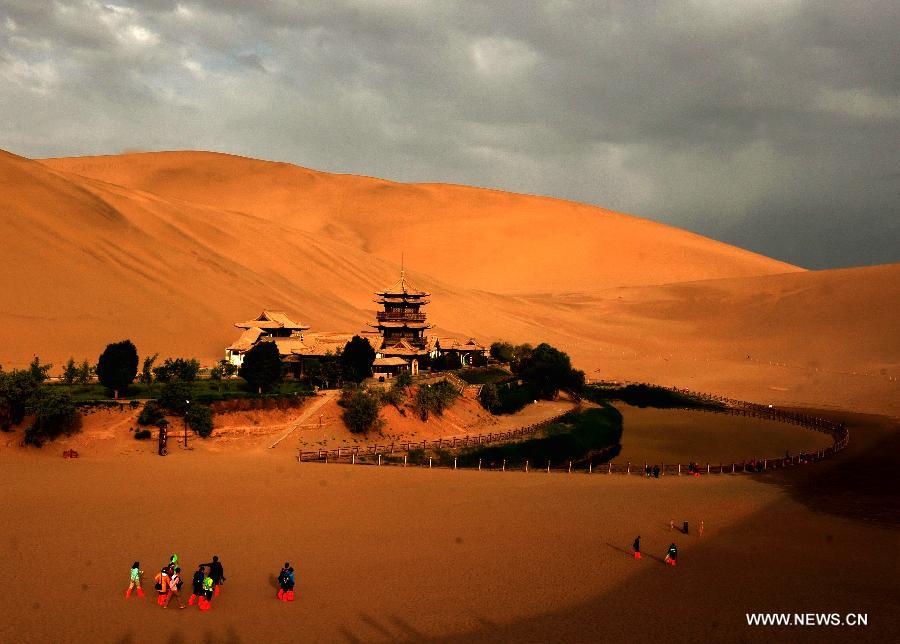 Tourists visit the scenic spot of the Mingsha Mountain and Crescent Spring in Dunhuang City, northwest China's Gansu Province, May 21, 2013. Dunhuang has received about 749,200 tourists in the first four months of 2013, increasing 58.63 percent year on year. (Xinhua/Nie Jianjiang)  