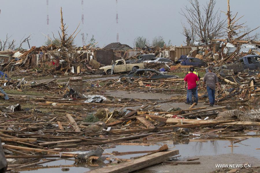 People walk through damage after a tornado in Moore, Oklahoma, the United States, on May 20, 2013. Twenty-four people were killed and 237 others injured when a massive tornado blasted the southern suburbs of Oklahoma City, the capital of the U.S. state of Oklahoma, on Monday, state officials said Tuesday. (Xinhua/Marcus DiPaola) 